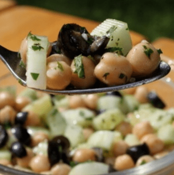 Chickpea cucumber salad on spoon with bowl in background