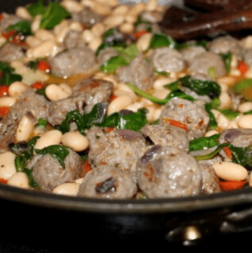 Italian sausage and white beans cooking in a skillet