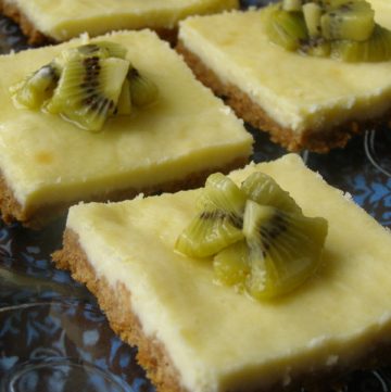 Slices of cut kiwi-glazed cheesecake bars on a serving platter.