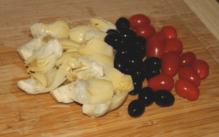 Artichoke salsa ingredients on a cutting board.
